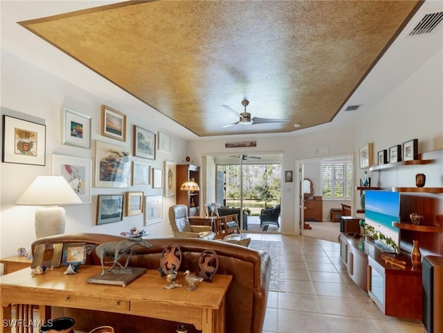 living room with ceiling fan, a textured ceiling, and light tile patterned floors