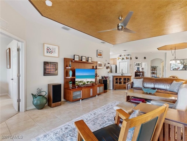 living room featuring light tile patterned flooring and ceiling fan with notable chandelier