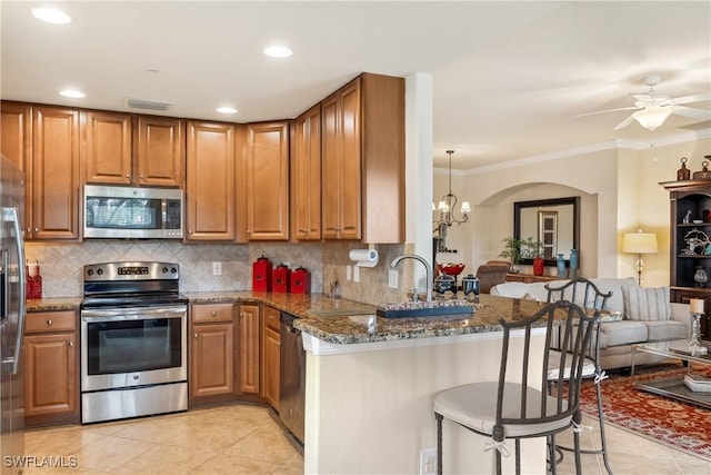 kitchen with decorative light fixtures, tasteful backsplash, a kitchen breakfast bar, dark stone counters, and stainless steel appliances