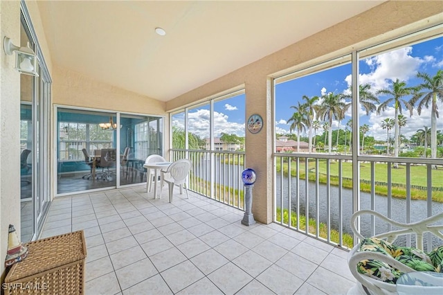 unfurnished sunroom with a water view, vaulted ceiling, and an inviting chandelier