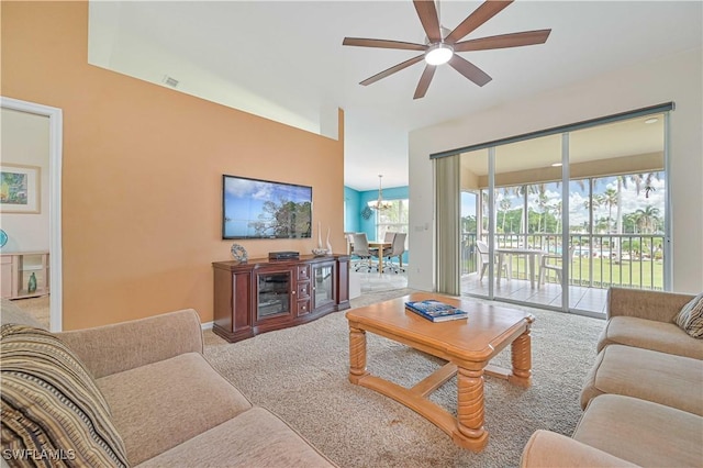 living room with ceiling fan with notable chandelier and carpet floors