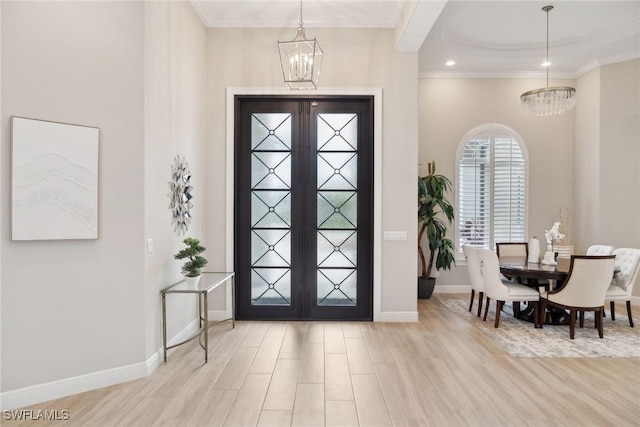 entrance foyer with a notable chandelier, ornamental molding, french doors, and light hardwood / wood-style flooring