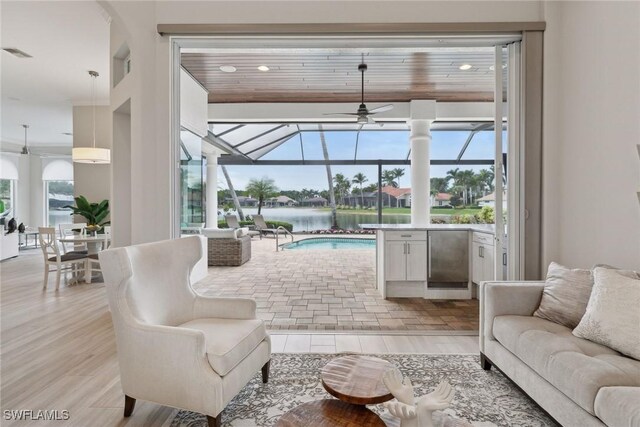 living room with ceiling fan, wood ceiling, a water view, and light hardwood / wood-style flooring