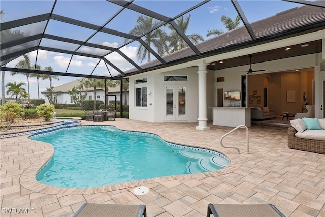 view of pool featuring ceiling fan, a patio area, outdoor lounge area, glass enclosure, and french doors