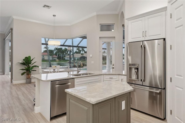 kitchen with stainless steel appliances, a center island, pendant lighting, white cabinets, and sink