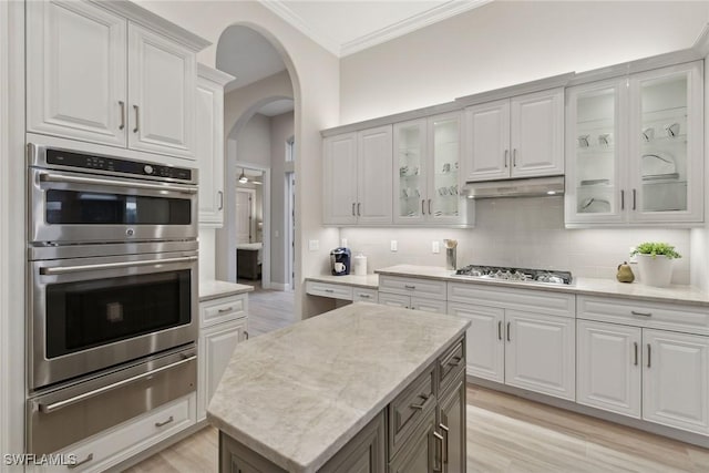 kitchen featuring white cabinets, a kitchen island, stainless steel appliances, decorative backsplash, and light hardwood / wood-style floors