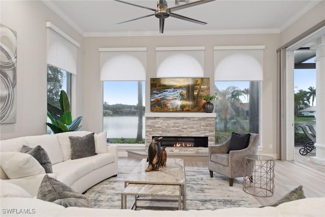 living room with a water view, ceiling fan, a fireplace, and crown molding