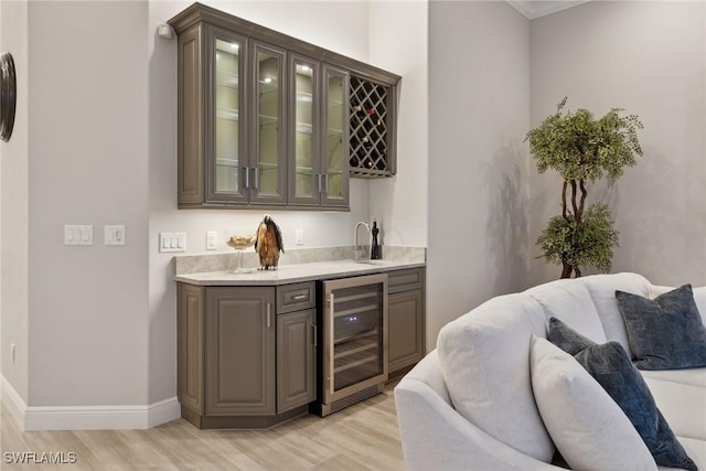 bar with light wood-type flooring, wine cooler, and sink