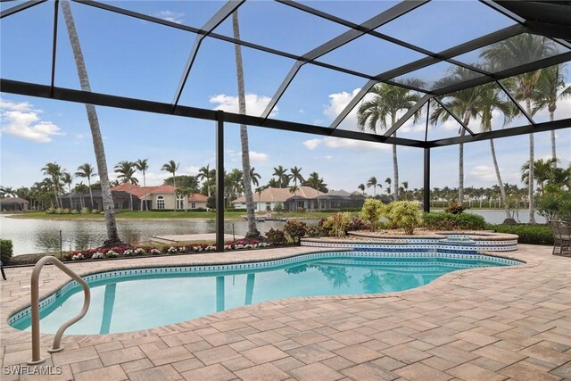 view of swimming pool featuring glass enclosure, a water view, and a patio