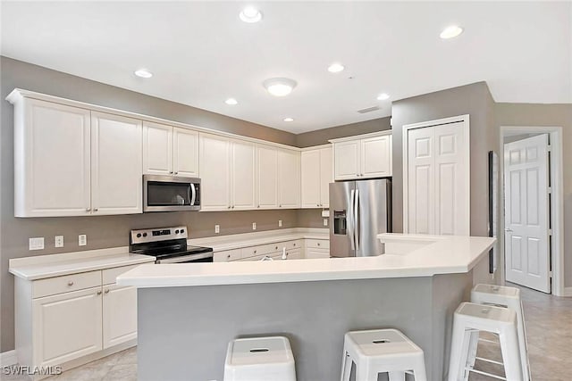 kitchen featuring an island with sink, a kitchen breakfast bar, stainless steel appliances, and white cabinetry