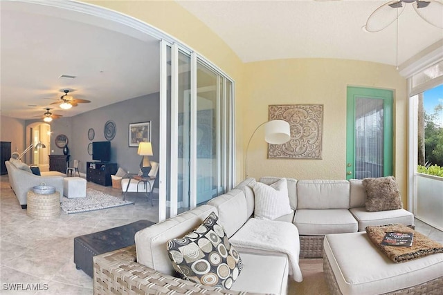 living room featuring ceiling fan, light tile patterned floors, and vaulted ceiling