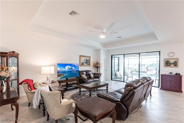 tiled living room featuring ceiling fan and a tray ceiling