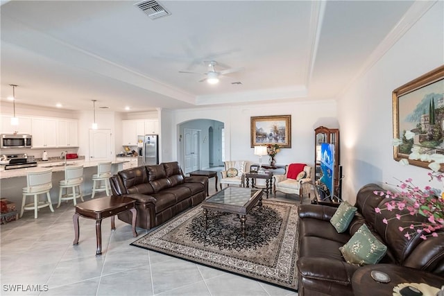 living room with ceiling fan, light tile patterned flooring, ornamental molding, and a raised ceiling