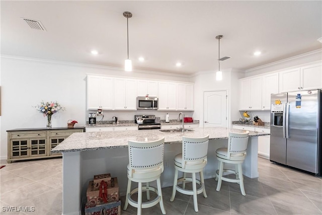 kitchen featuring an island with sink, appliances with stainless steel finishes, decorative light fixtures, white cabinets, and sink