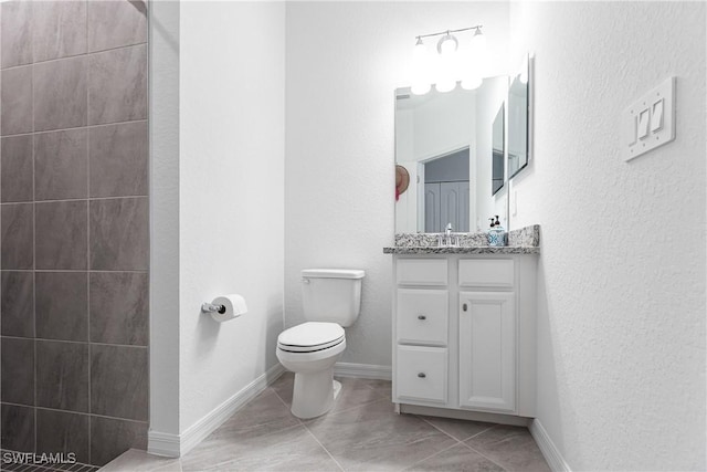 bathroom with toilet, vanity, and tile patterned flooring