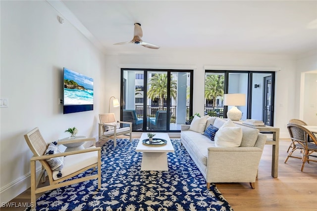 living room featuring wood-type flooring, ceiling fan, and crown molding