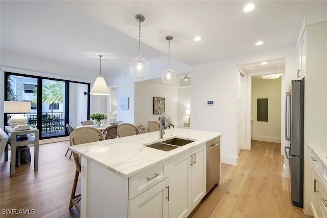 kitchen featuring sink, decorative light fixtures, white cabinetry, a kitchen island with sink, and appliances with stainless steel finishes