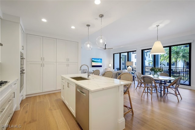 kitchen featuring stainless steel appliances, a kitchen island with sink, white cabinetry, and sink