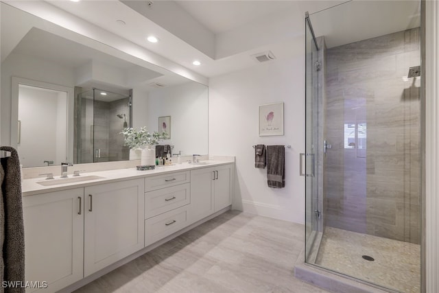 bathroom featuring a shower with door and vanity