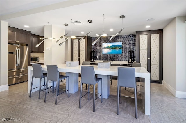 kitchen with decorative light fixtures, a large island, a breakfast bar area, dark brown cabinetry, and appliances with stainless steel finishes