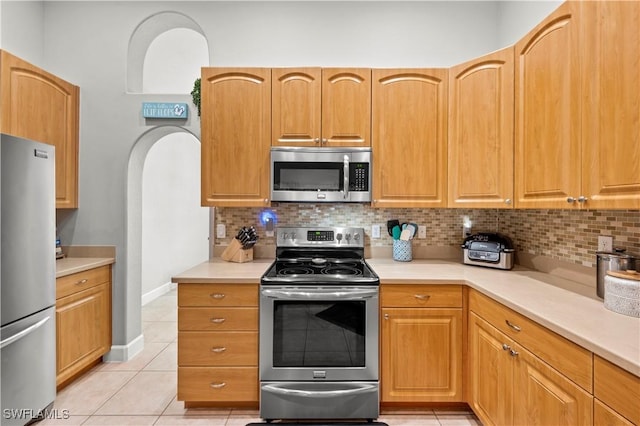 kitchen with light tile patterned flooring, appliances with stainless steel finishes, and tasteful backsplash