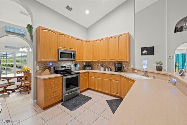 kitchen with sink, light tile patterned floors, high vaulted ceiling, and appliances with stainless steel finishes