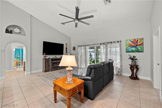 tiled living room with ceiling fan and high vaulted ceiling