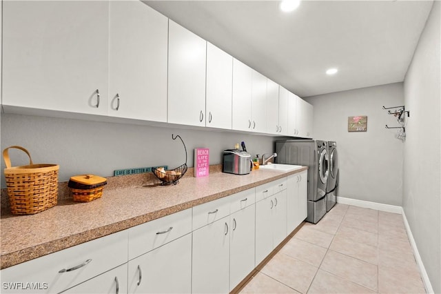 laundry area featuring cabinets, light tile patterned floors, sink, and washing machine and dryer