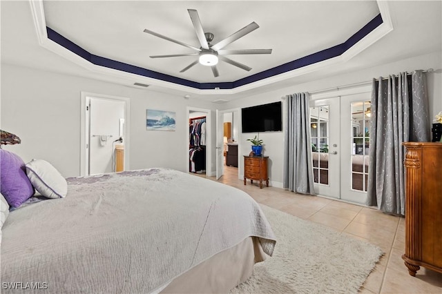 tiled bedroom featuring ceiling fan, ensuite bathroom, french doors, a tray ceiling, and access to exterior