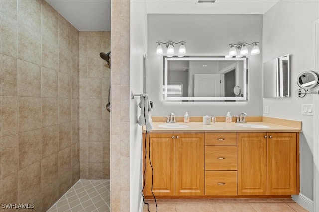 bathroom featuring vanity, a tile shower, and tile patterned flooring