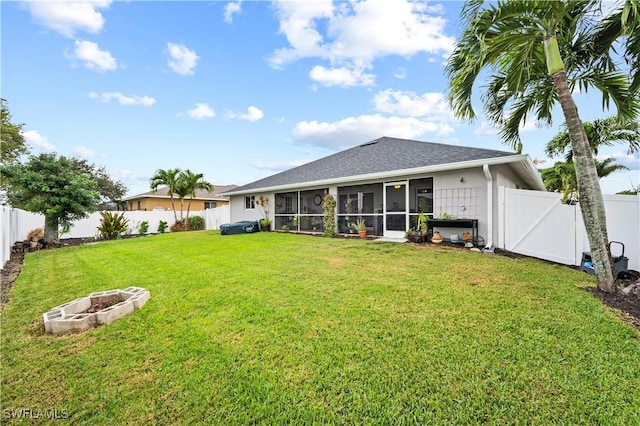 back of house featuring a sunroom, a fire pit, and a yard