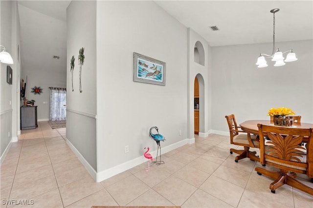 dining area featuring a high ceiling, light tile patterned floors, and a notable chandelier