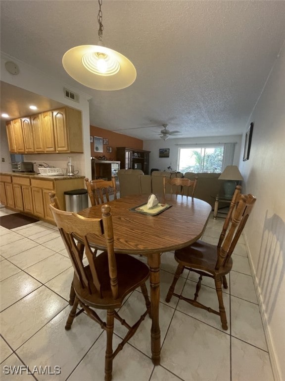 dining area with a textured ceiling, ceiling fan, and light tile patterned floors