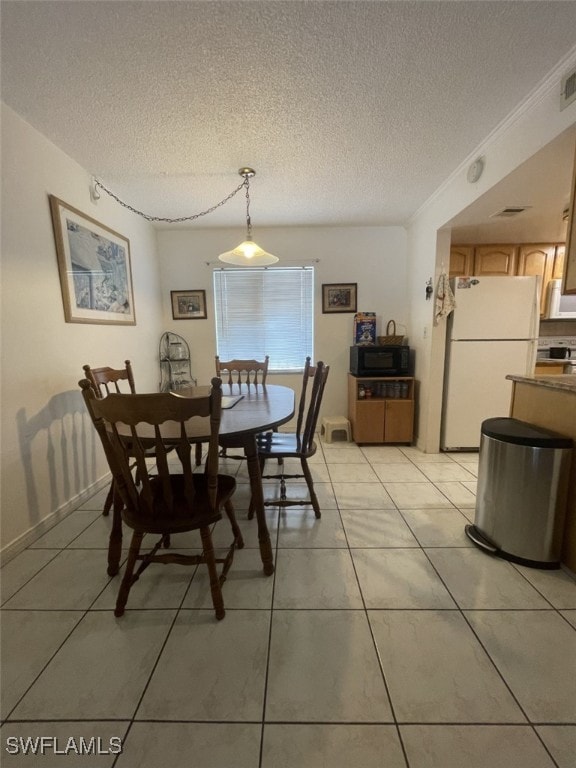 tiled dining room featuring a textured ceiling and ornamental molding