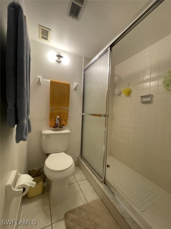 bathroom featuring toilet, an enclosed shower, and tile patterned flooring