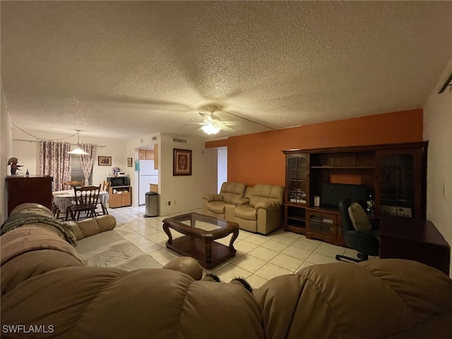 living room with ceiling fan, light tile patterned flooring, and a textured ceiling