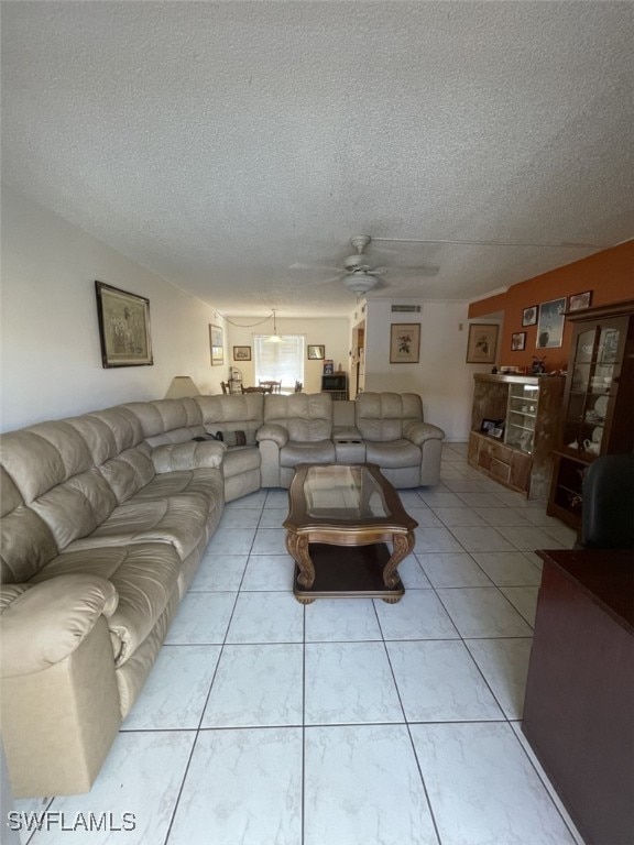 living room featuring a textured ceiling, ceiling fan, and light tile patterned floors