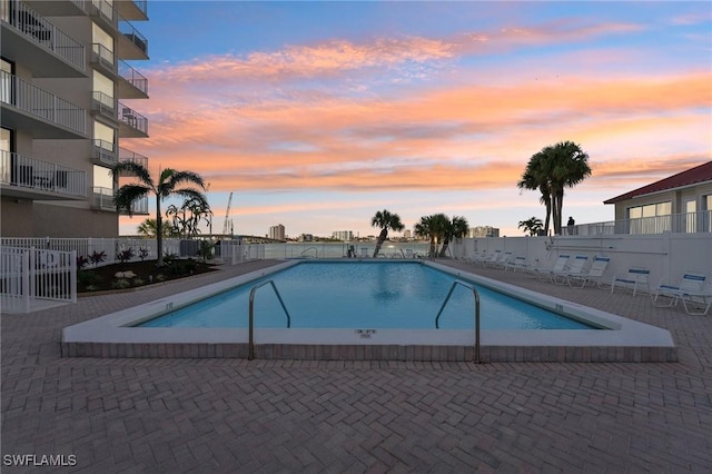 pool at dusk featuring a patio