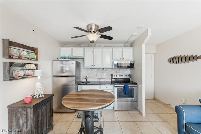 kitchen featuring appliances with stainless steel finishes, white cabinetry, backsplash, ceiling fan, and light tile patterned floors