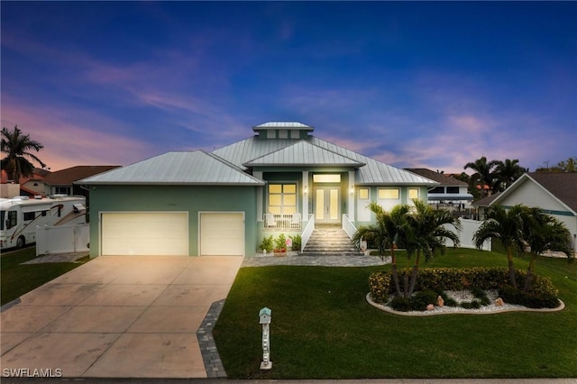 view of front of property with a garage, a lawn, and french doors