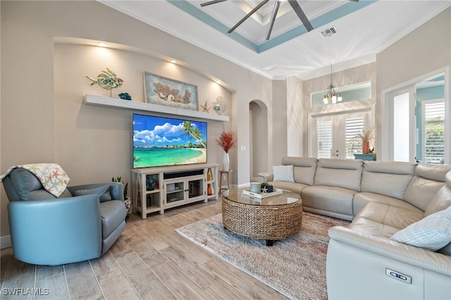 living room featuring crown molding, ceiling fan, light wood-type flooring, and a tray ceiling