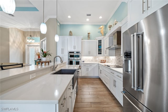 kitchen featuring decorative light fixtures, appliances with stainless steel finishes, wall chimney range hood, a large island, and white cabinets