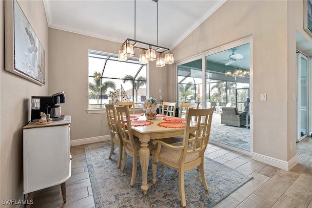 dining space featuring crown molding, lofted ceiling, a chandelier, and light hardwood / wood-style flooring