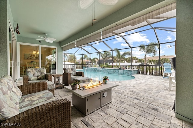 view of swimming pool featuring ceiling fan, glass enclosure, a patio area, an outdoor living space with a fire pit, and pool water feature