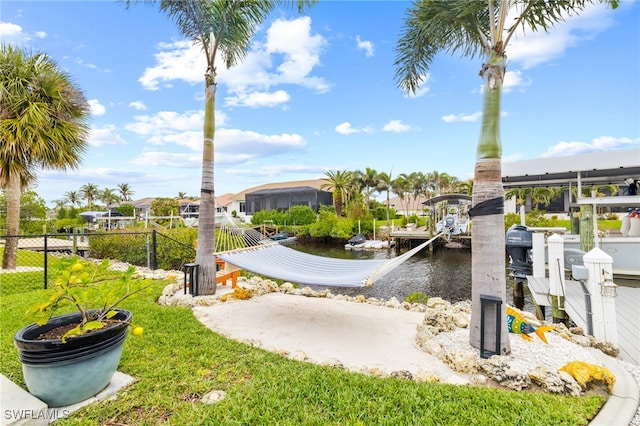 surrounding community with a water view, a yard, and a dock