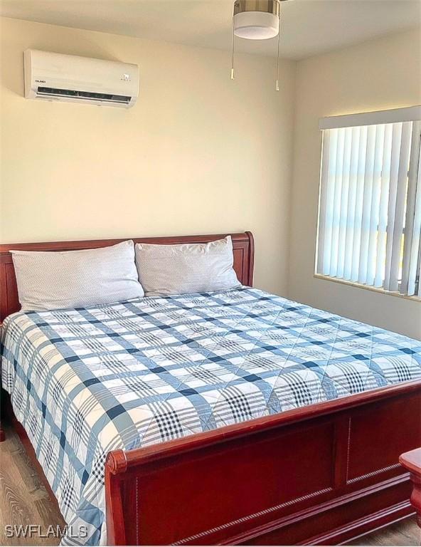 bedroom featuring hardwood / wood-style flooring and a wall mounted air conditioner