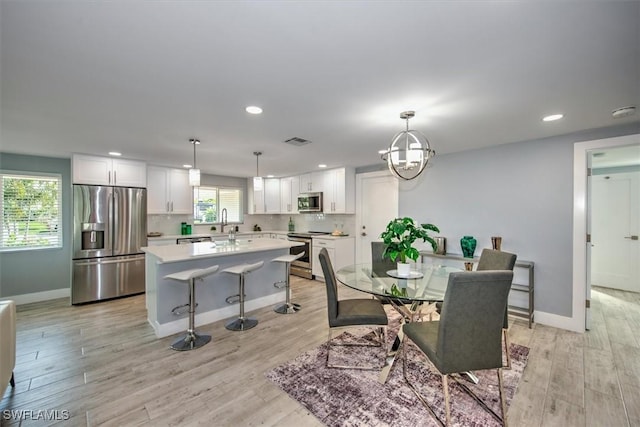 dining space featuring sink, light hardwood / wood-style flooring, and a chandelier