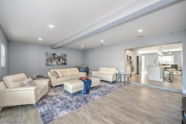 living room with light hardwood / wood-style floors and beamed ceiling