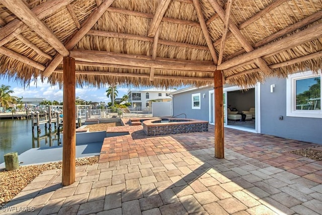 view of patio with a boat dock, a water view, an in ground hot tub, and a gazebo