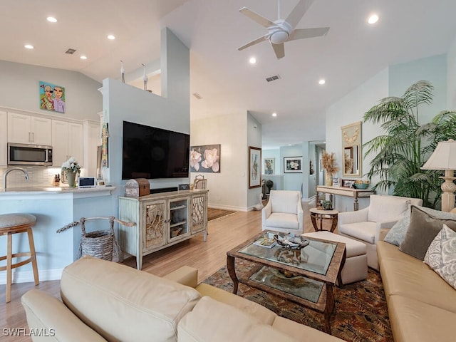 living room featuring ceiling fan, lofted ceiling, and light wood-type flooring